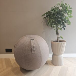 Modern huidkleurige poef en grote groene plant in ivoorkleurige geprofileerde pot, interieurstijl, natuurlijk licht, woondecoratie, comfortabele zithoek, design meubel, natuurthema, stijlvolle inrichting, woonideeën, woningdecoratie.
