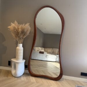 Spiegel met houten rand en decoratieve vaas met pampasgras in Scandinavisch geïnspireerd interieur.