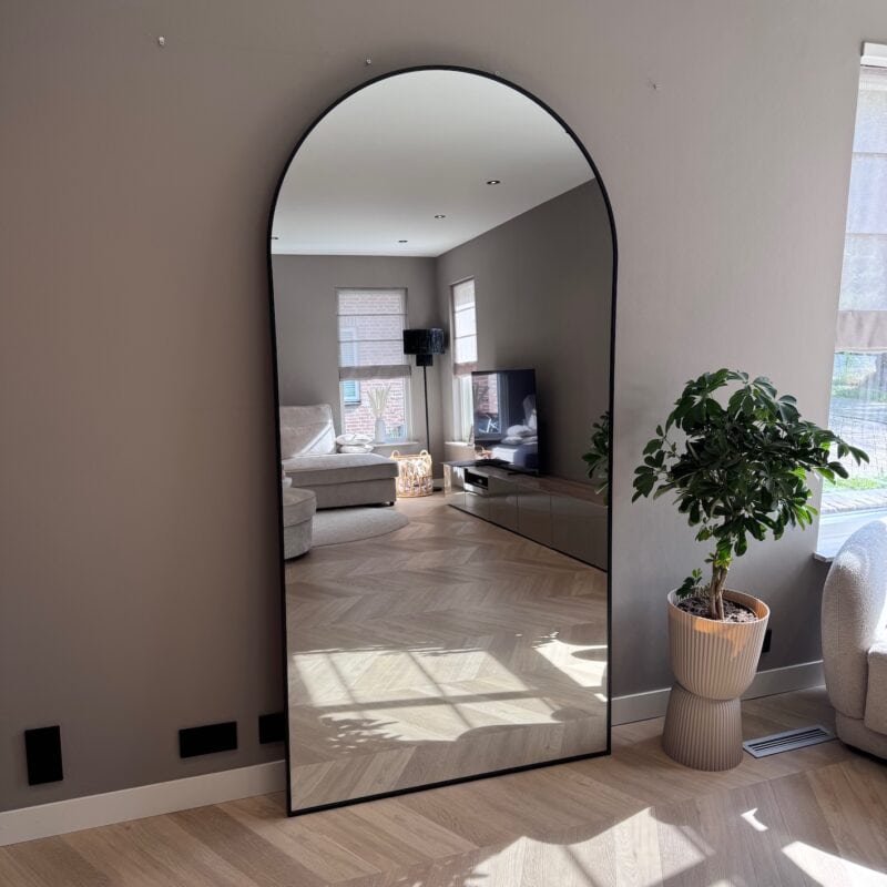 Groot vrijstaand muurspiegel met arkerand voor modern interieur, weerspiegelt woonkamer met comfortabele zitbank, tv en natuurlijke lichtinval. Perfect voor elegant en functioneel huisdecor.