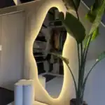 Unieke spiegel met randverlichting, modern interieur met planten en witte accessoires. Grote spiegel met warme randverlichting, modern interieur met planten en witte decoratie, perfect voor een stijlvolle en sfeervolle woonkamer.