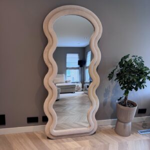 Elegant houten muurspiegel met golvende rand, modern interieurontwerp, woondecoratie, stijlvolle woonkamer, natuurlijke houtafwerking, sfeercreatie, design spiegel, trendy interieuraccessoire, spiegel met unieke vorm, sfeer en stijl.