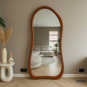 Reflexieve vloer spiegel met houten frame in een modern woonkamer, stijlvolle woninginrichting, natuurlijk licht, minimalistisch interieurdesign, zwart stopcontact en ventilatierooster zichtbaar, sfeervol en elegant.