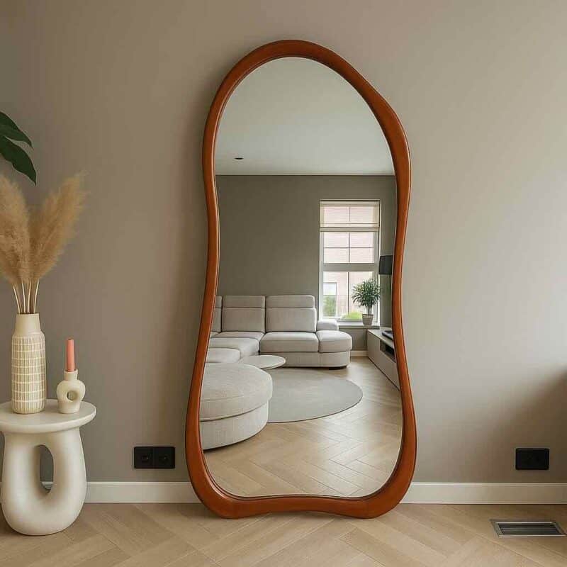 FLOW-wood-mirror Reflexieve vloer spiegel met houten frame in een modern woonkamer, stijlvolle woninginrichting, natuurlijk licht, minimalistisch interieurdesign, zwart stopcontact en ventilatierooster zichtbaar, sfeervol en elegant.